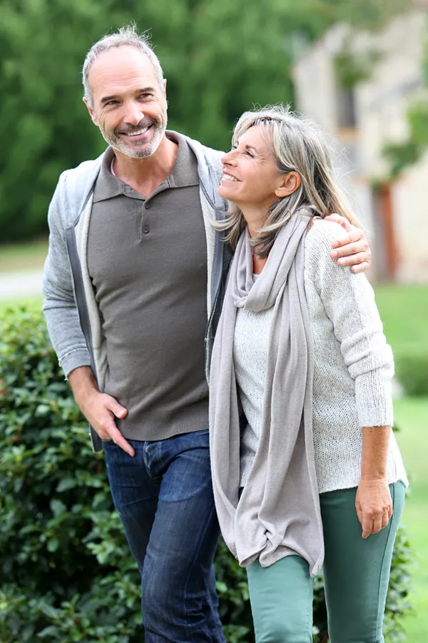 Bioidentical-Hormone-Therapy-Treatment A mature couple in gray toned clothes and jeans walk happily outside, happy with their successful bioidentical hormone treatments from Julie Kane, NP of Bird Island Wellness in Calgary.