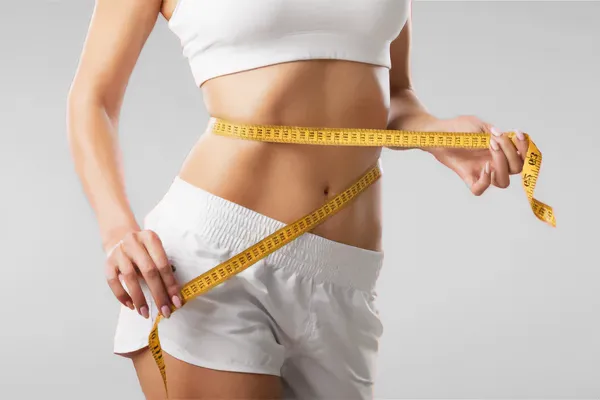 Low-Dose-Naltrexone-for-Weight-Loss-Doctor A woman wraps a measuring tape around her waist to show the success of her Low Dose Naltrexone for Weight Loss treatments from Julie Kane, NP of Bird Island Wellness in Calgary.