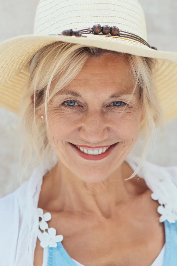 Menopause-Treatment A beautiful, smiling older woman with blonde hair and a sunhat, happy with menopause treatment from Julie Kane, NP of Bird Island Wellness in Calgary.