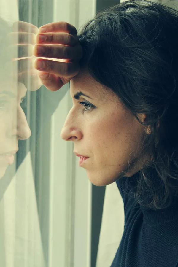 PCOS-Treatment A brunette woman in a thin dark turtleneck looks out the window with a serious expression, suffering from PCOS. Get treatment for Polycistic Ovarian Syndrome/PCOS from Julie Kane, NP of Bird Island Wellness in Calgary.